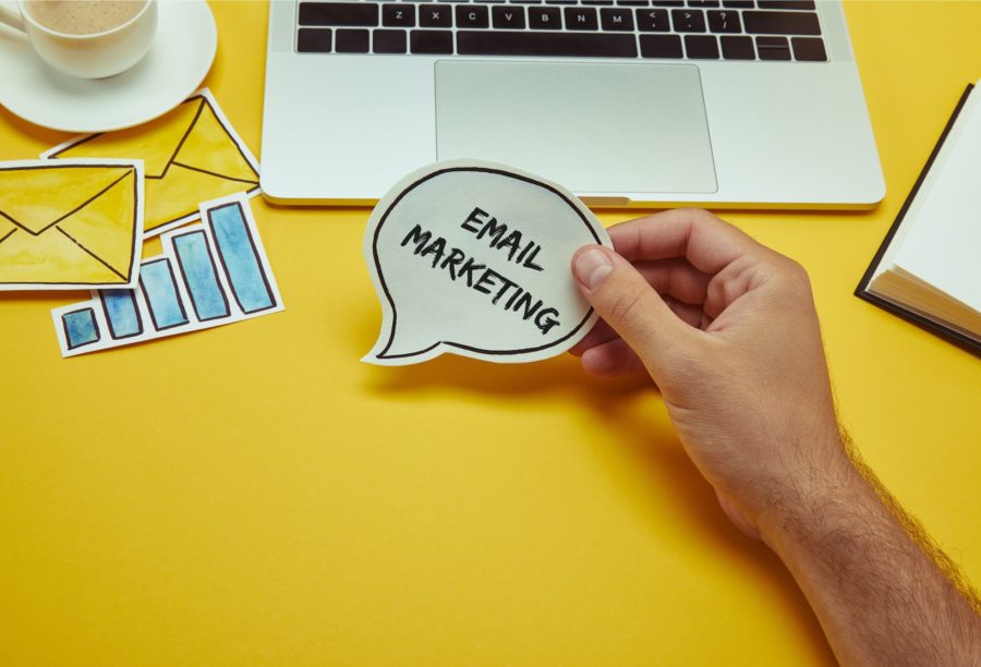 cropped-image-of-man-holding-speech-bubble-with-email-marketing-lettering-near-laptop-900x612